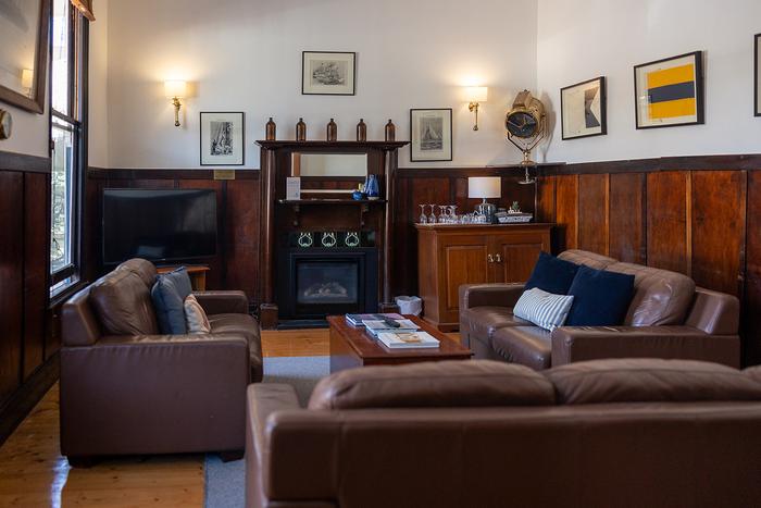 Heritage guest lounge with leather sofas, fireplace and maritime artwork