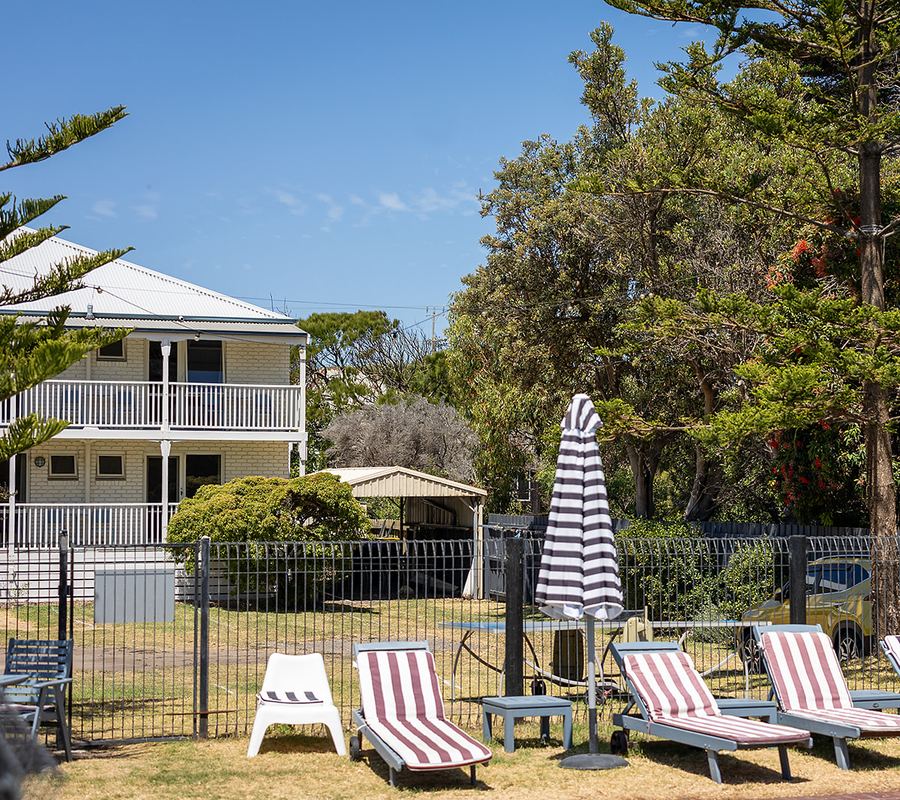 Poolside loungers at Point Lonsdale Guest House with heritage motel building in background